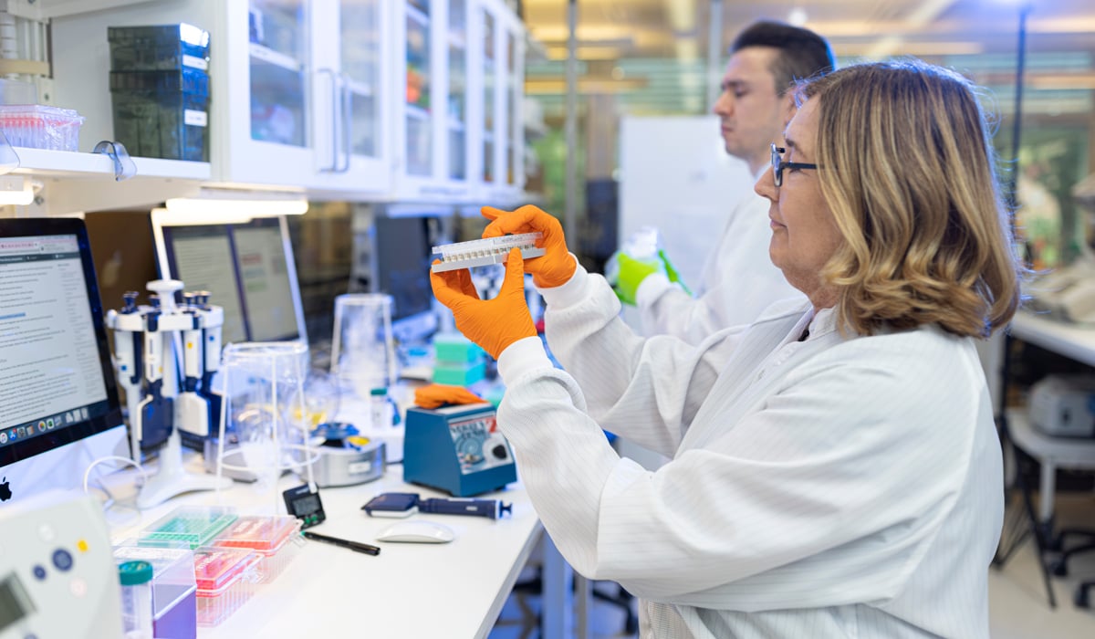 A woman in a lab holding a tube of liquid.