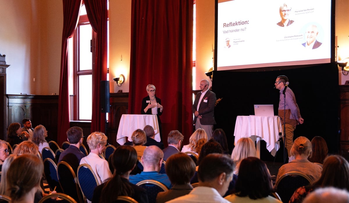 Bild på scenen under konferensen, där sjukhusdirektörerna står och pratar.