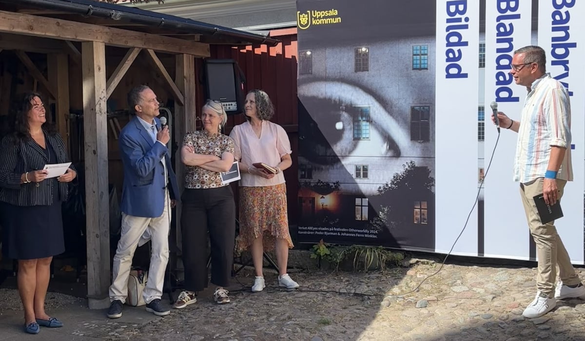 En grupp människor står framför en byggnad och pratar i ett panelsamtal.