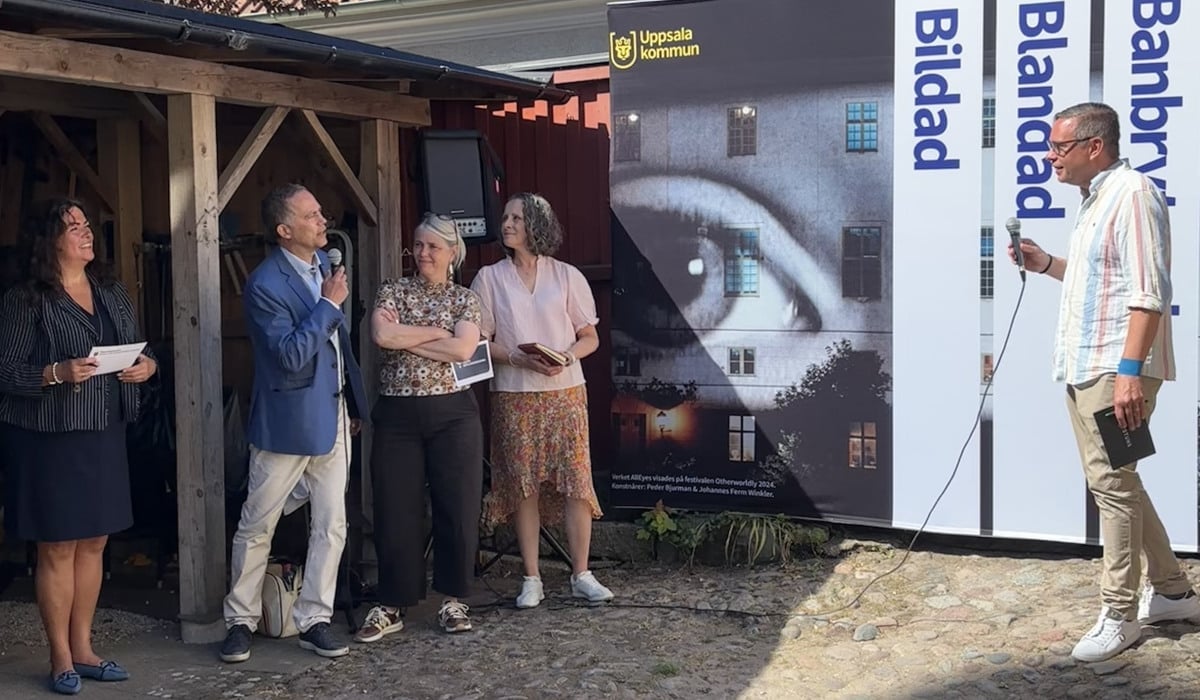 En grupp människor står framför en byggnad och pratar i ett panelsamtal.